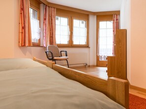 Ein Schlafzimmer mit einem Bett, einem Sessel und einem Fenster mit Vorhängen.