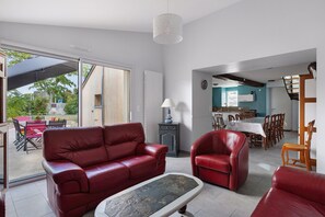 Un vaste espace de vie comprenant un canapé en cuir rouge, une table basse et un coin repas avec une table et des chaises.