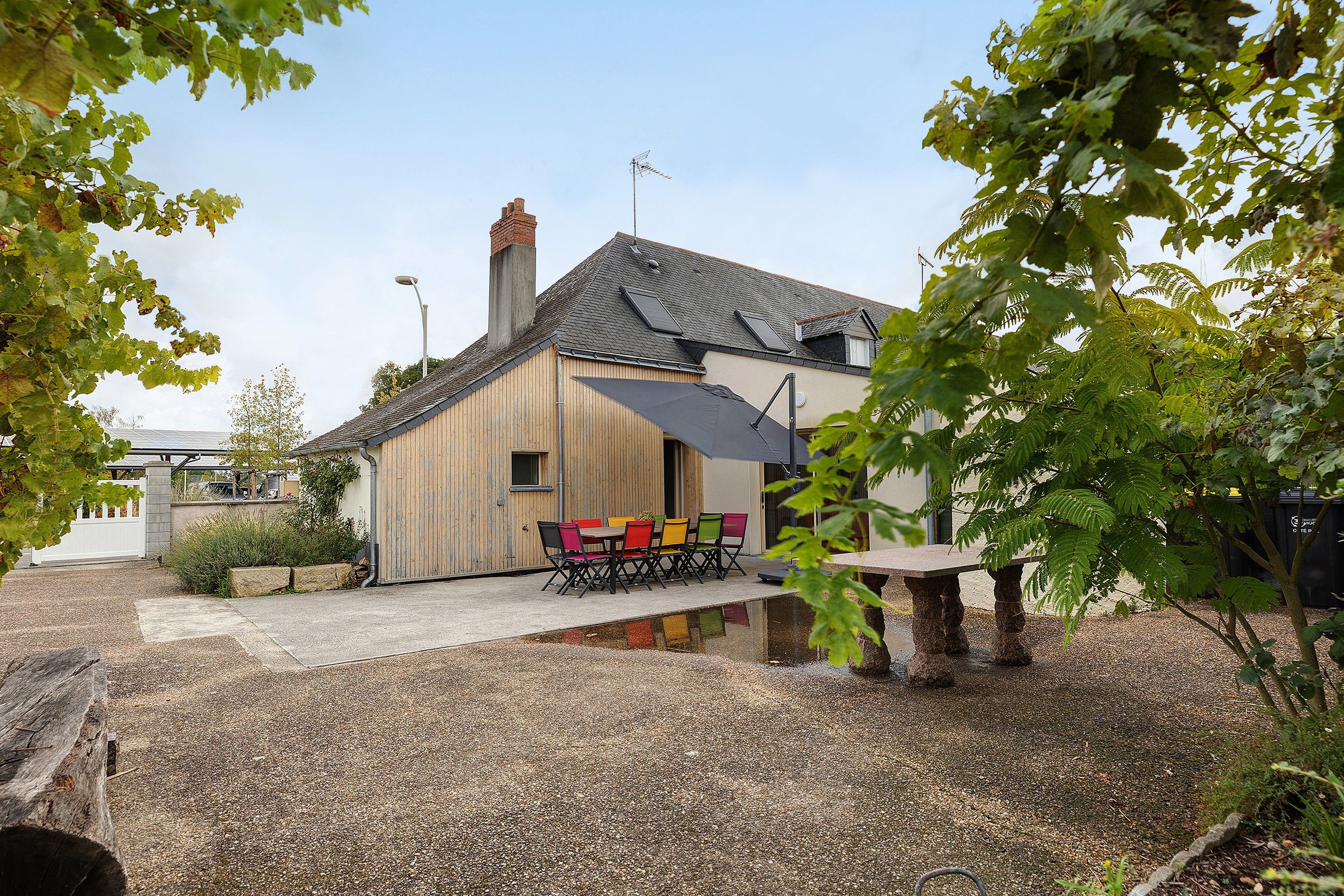 Un bâtiment rustique avec un toit en pente, une façade en bois et une allée gravillonnée.