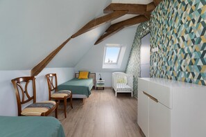 Une chambre mansardée chaleureuse avec un plafond en pente, une chaise en bois, un lit, un berceau et un mur orné d’un motif.