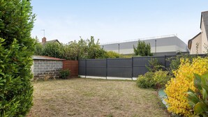 Ein Wohngarten mit umzäunter Fläche, einer Backsteinmauer und verschiedenen Sträuchern.