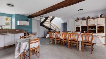 A dining area with a wooden table and chairs, a kitchen with white cabinets, and a spiral staircase.