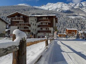 A snow-covered building with multiple balconies and a mountain backdrop. - Haus Evita Appartement/Fewo 4-Bettwohnung Nr. 60 by Interhome (Saas-Grund)