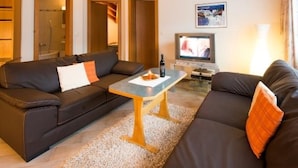 A living room with a sofa, a coffee table, a TV, and a lamp. - Haus Evita Appartement/Fewo 4-Bettwohnung Nr. 60 by Interhome (Saas-Grund)