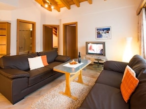 Ein Wohnzimmer mit einer Couch, einem Couchtisch, einem Fernseher und einer Lampe.