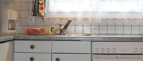 A kitchen with white cabinets, a sink, and a stove.