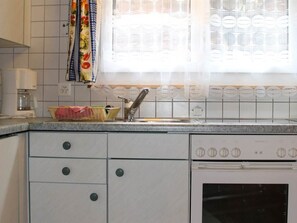 Eine Küche mit weißen Schränken, einer Spüle und einem Herd.