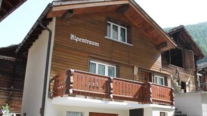 Un bâtiment en bois à deux étages, doté d’un balcon et d’une enseigne sur laquelle on peut lire « Alpenraum ».