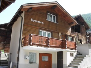 Ein zweistöckiges Holzhaus mit Balkon und einem Schild, auf dem 'Alpenraum' steht.