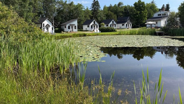 A row of white cabins with a pond in the foreground. - The Summit Suite | Walk to Rangeley Lake • ATV & Sled Access (Rangeley)