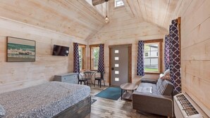 A cozy cabin interior with a bed, sofa, and a small dining area. - The Summit Suite | Walk to Rangeley Lake • ATV & Sled Access (Rangeley)