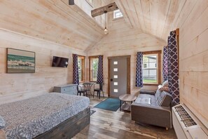 A cozy cabin interior with a bed, sofa, and a small dining area. - The Summit Suite | Walk to Rangeley Lake • ATV & Sled Access (Rangeley)