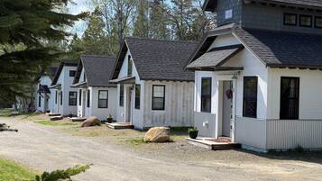 A row of white cabins with dark roofs, each with a porch and a small front door.