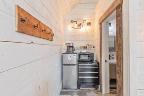 Eine kleine Küche mit Kühlschrank, Mikrowelle und Schubladen aus Edelstahl.