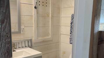 Et badeværelse med hvid vask, spejl og toilet.
