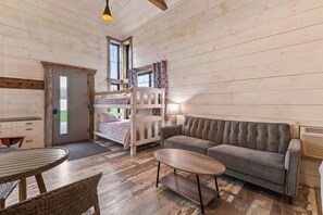 A room with bunk beds, a sofa, a round table, and a chair.