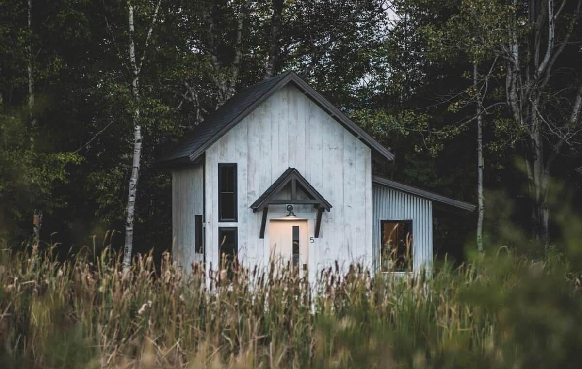 A rustic wooden cabin with a gabled roof, a front door, and a small porch area.