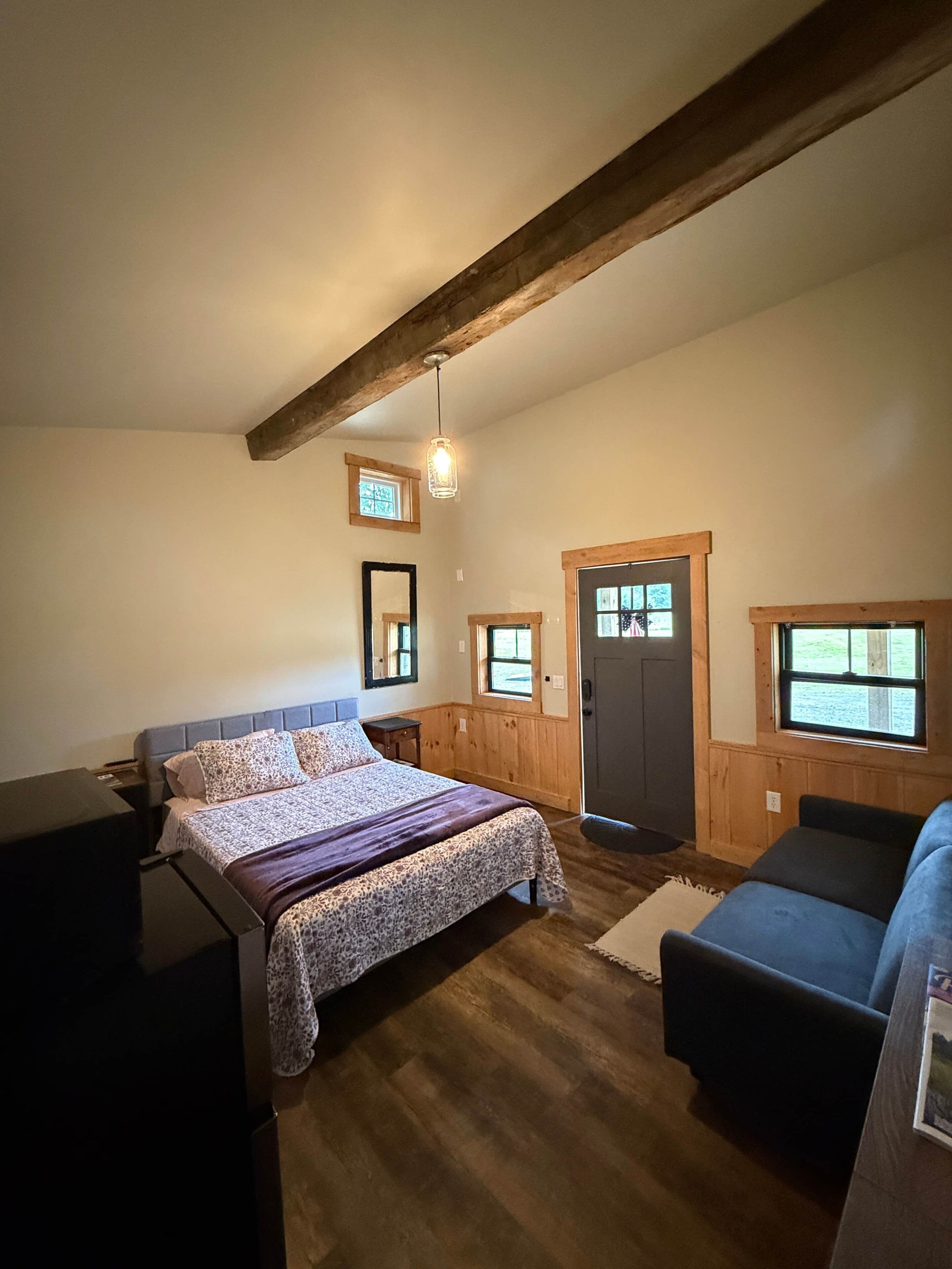 A bedroom with a bed, a desk, a chair, and a window.