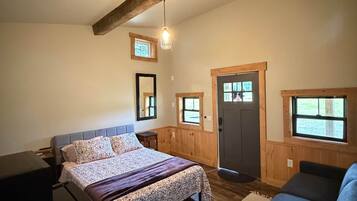 A bedroom with a bed, a desk, a chair, and a window.