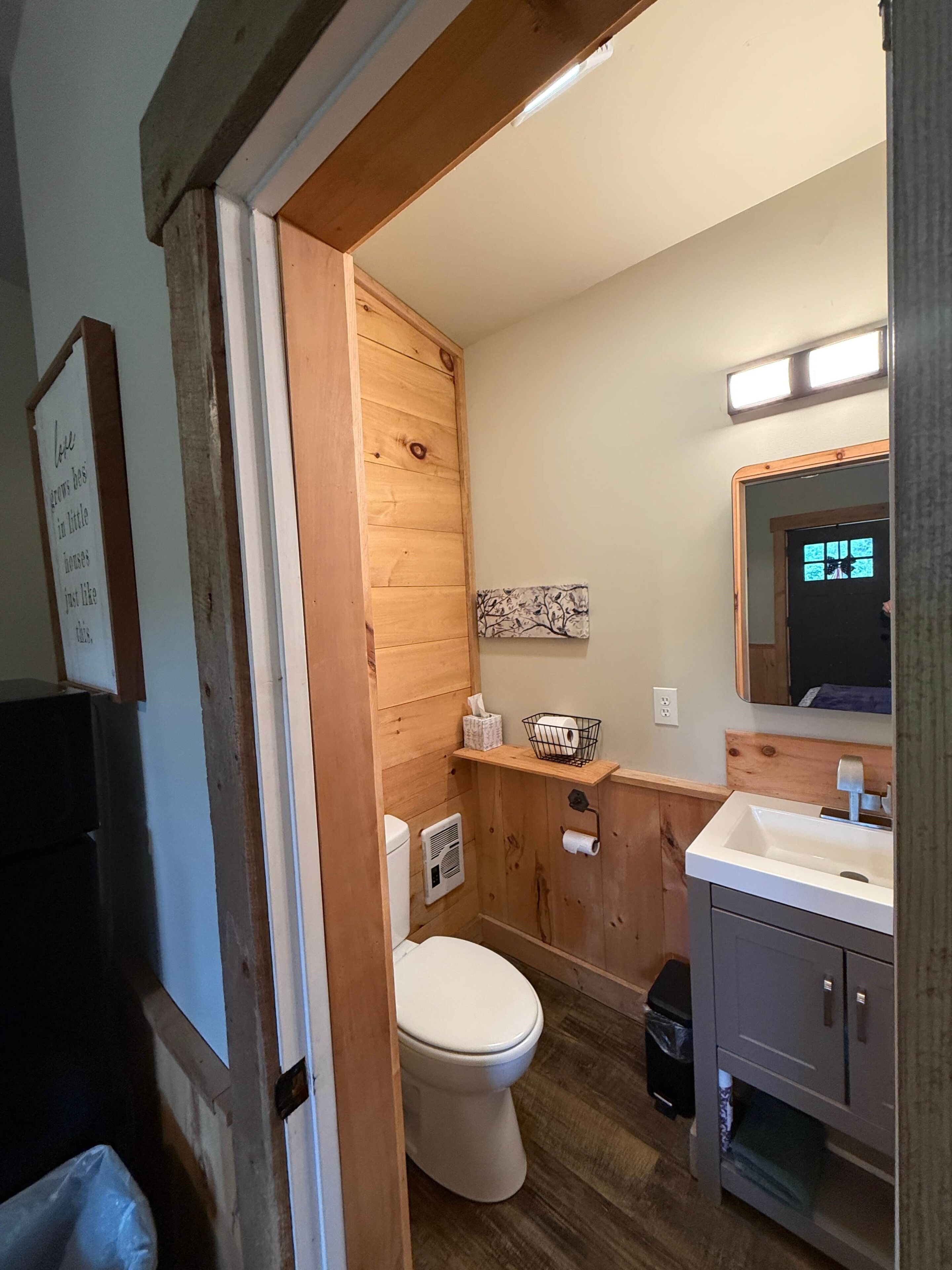 Un baño con tocador de madera, inodoro y lavamanos.