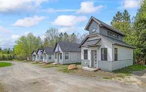Une rangée de chalets de plain-pied, avec une allée en gravier, entourés d’arbres.