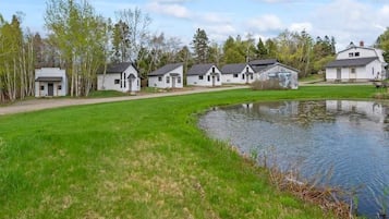 A row of white cabins with a pond in the foreground.