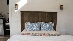 Un letto con testiera in legno, due cuscini decorati e una coperta a motivi floreali.