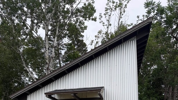 A single-story building with a front door, two windows on the side, and a small porch area.