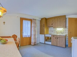 Una cocina compacta con muebles de madera, un refrigerador blanco y un comedor con mesa y sillas.