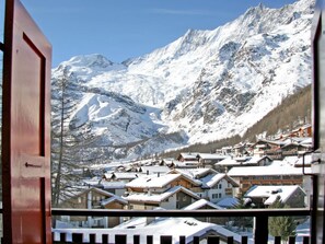 Un pueblo de montaña con edificios cubiertos de nieve y una vista despejada de los picos circundantes.