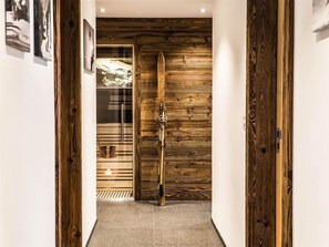 A hallway with a wooden door and a surfboard leaning against it. - Heinrida Appartement/Fewo 10-Bettwohnung by Interhome (Saas-Fee)