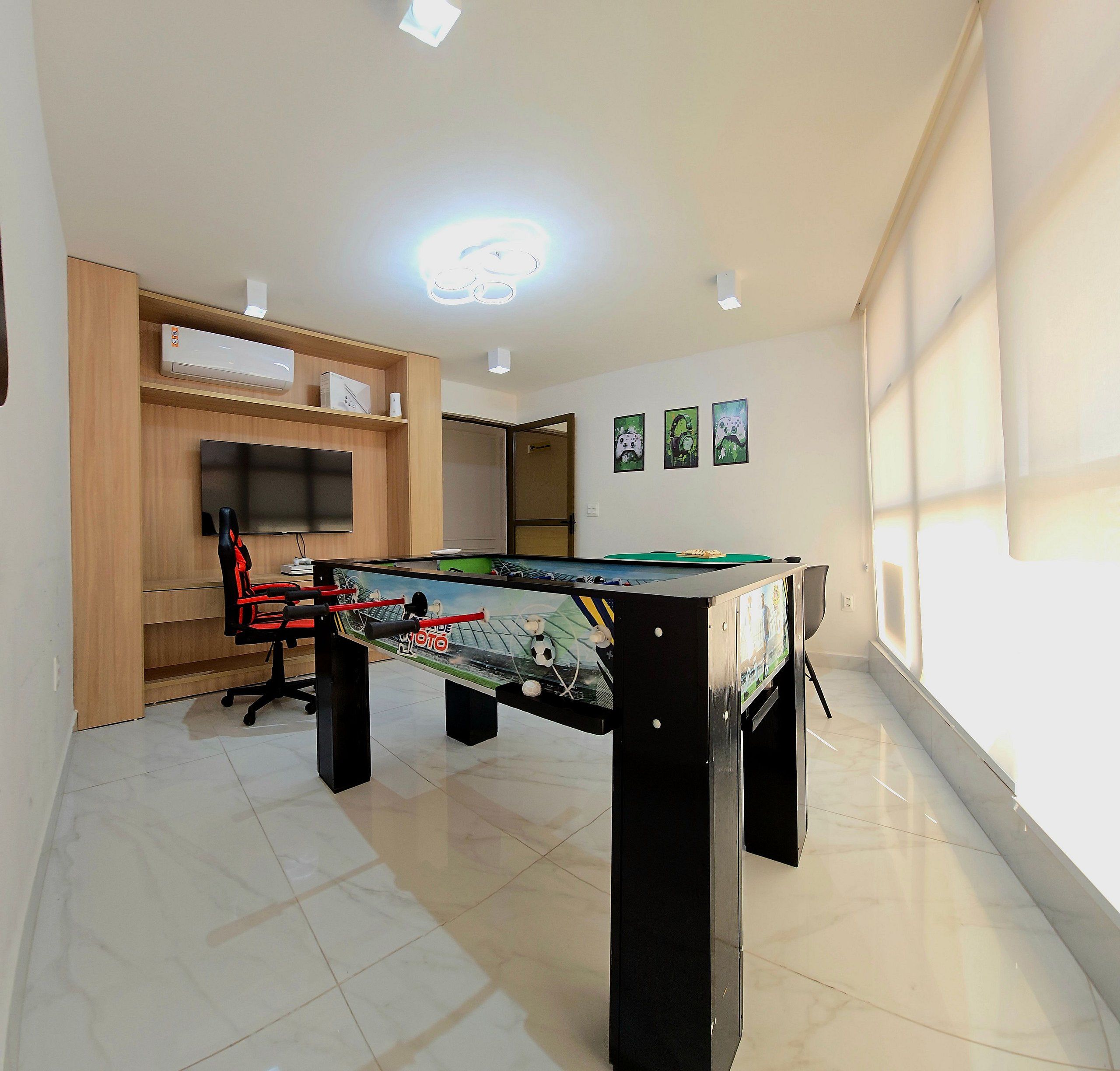 Una habitación con mesa de fútbol, televisor de pantalla plana y una silla gamer.