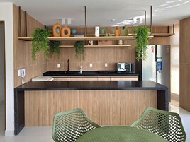 Uma cozinha moderna com uma ilha central, armários de madeira e plantas penduradas.