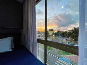 A room with a large window overlooking a street and a sunset. - Dva Flats By Hosppedar (Cabedelo)