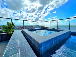 Piscina infinita no terraço com vista desimpedida da cidade e do oceano.