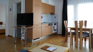 A modern kitchen with wooden cabinets, a built-in oven, and a dining area with a table and chairs. - Fee-Rien Appartement/Fewo 4-Bettwohnung by Interhome (Saas-Fee)