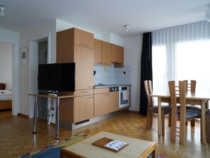 A modern kitchen with wooden cabinets, a built-in oven, and a dining area with a table and chairs. - Fee-Rien Appartement/Fewo 4-Bettwohnung by Interhome (Saas-Fee)