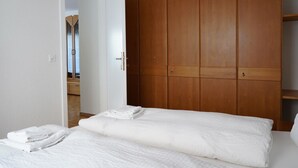 A bedroom with a bed, a wardrobe, and a door leading to another room. - Fee-Rien Appartement/Fewo 4-Bettwohnung by Interhome (Saas-Fee)