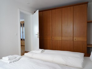 A bedroom with a bed, a wardrobe, and a door leading to another room. - Fee-Rien Appartement/Fewo 4-Bettwohnung by Interhome (Saas-Fee)