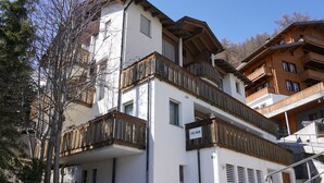 A multi-story building with balconies, a sign indicating 'FEUERIEN,' and a snow-covered ground. - Fee-Rien Appartement/Fewo 4-Bettwohnung by Interhome (Saas-Fee)