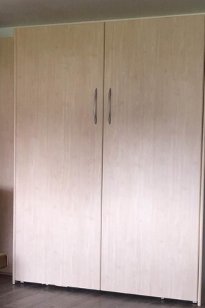 Ein großer, heller Kleiderschrank mit zwei Griffen.