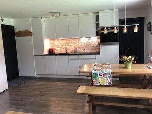 Eine moderne Küche mit weißen Schränken, einer Steinrückwand und einem eingebauten Backofen.