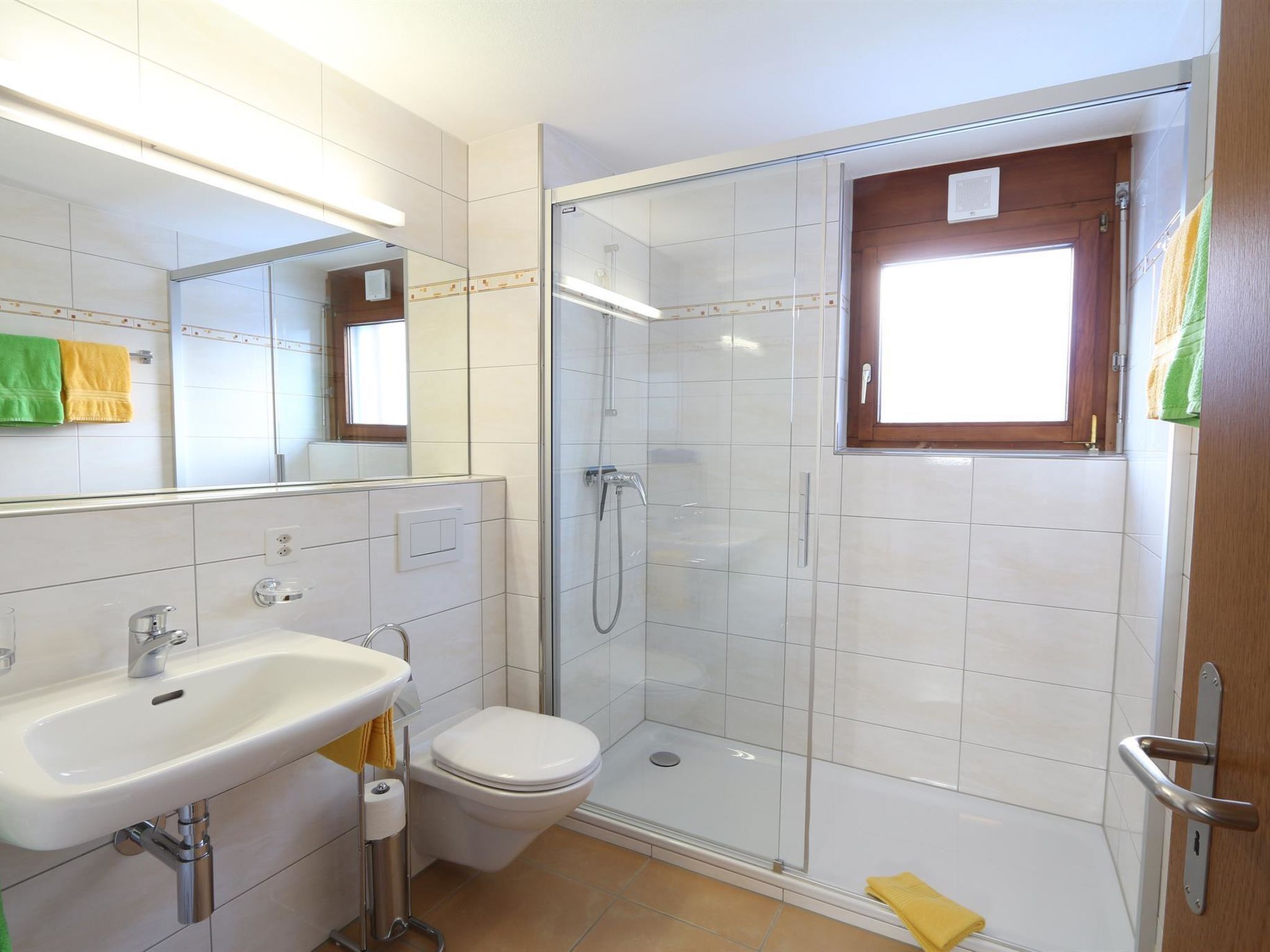 Ein modernes Badezimmer mit einer gläsernen Duschkabine, einem weißen Waschbecken und einer Toilette.
