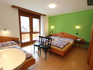 Ein Zimmer mit zwei Betten, einem Tisch, Stühlen und einer Badewanne.