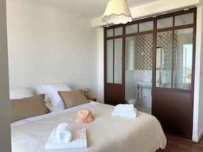Ett hotellrum med en säng, en garderob, ett badrum med handfat och utsikt genom fönstret.