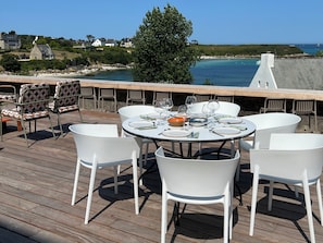 Una terrazza con tavolo apparecchiato per mangiare, affacciata su un paesaggio costiero.
