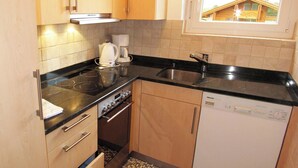 Cocina compacta con estufa, horno, cafetera y lavavajillas.
