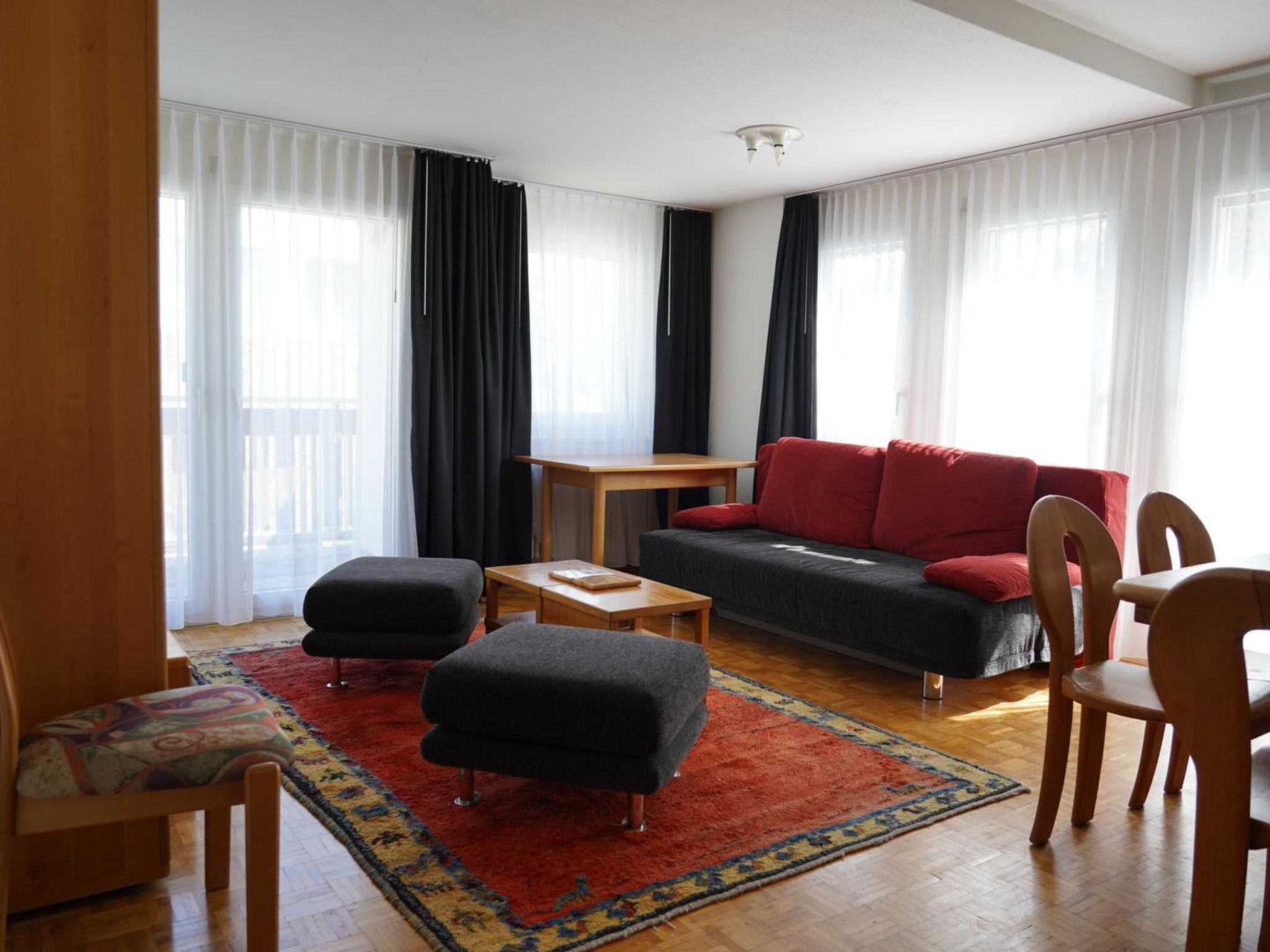Un salon moderne comprenant un canapé, un pouf, une table basse et des fauteuils.