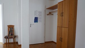 Una habitación con un armario de madera, una silla y una puerta con avisos.
