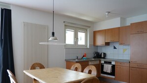 Cocina compacta con mesa, sillas, ventana y armarios de madera.